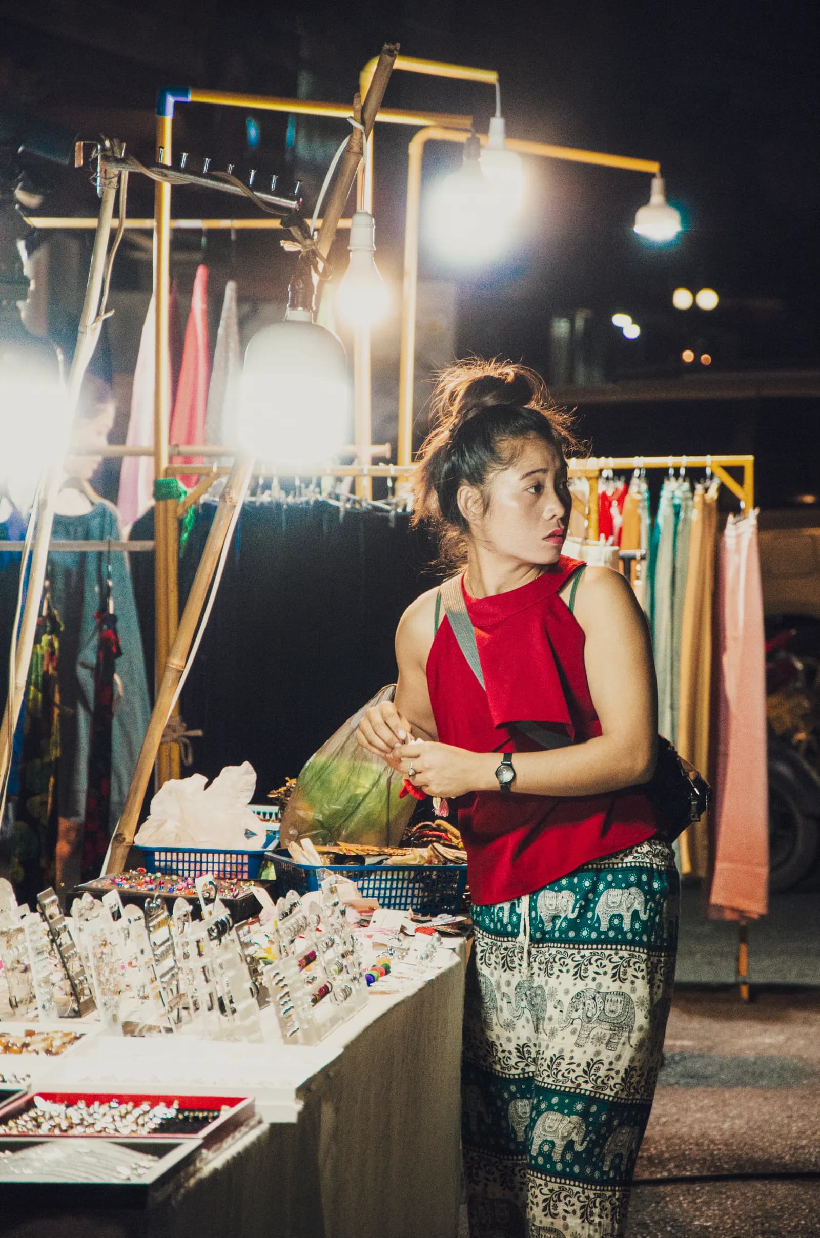 Woman shopping at a brightly lit night market in Chiang Mai