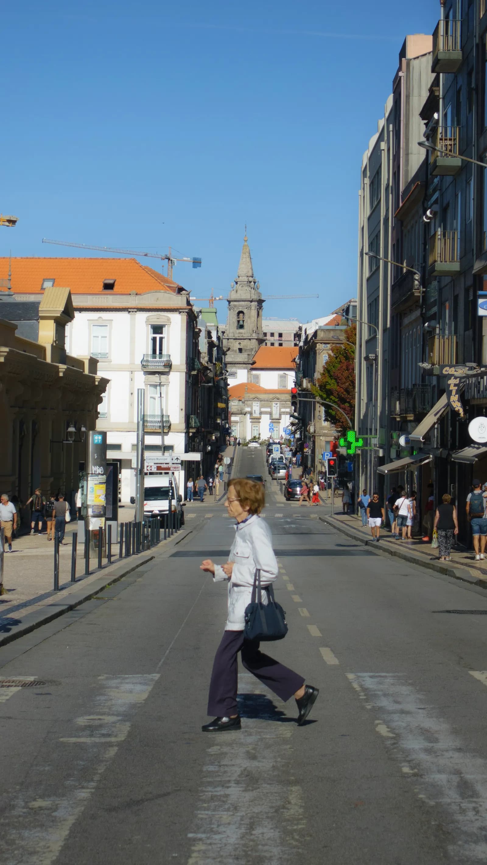 Woman crossing a sunlit street in Porto
