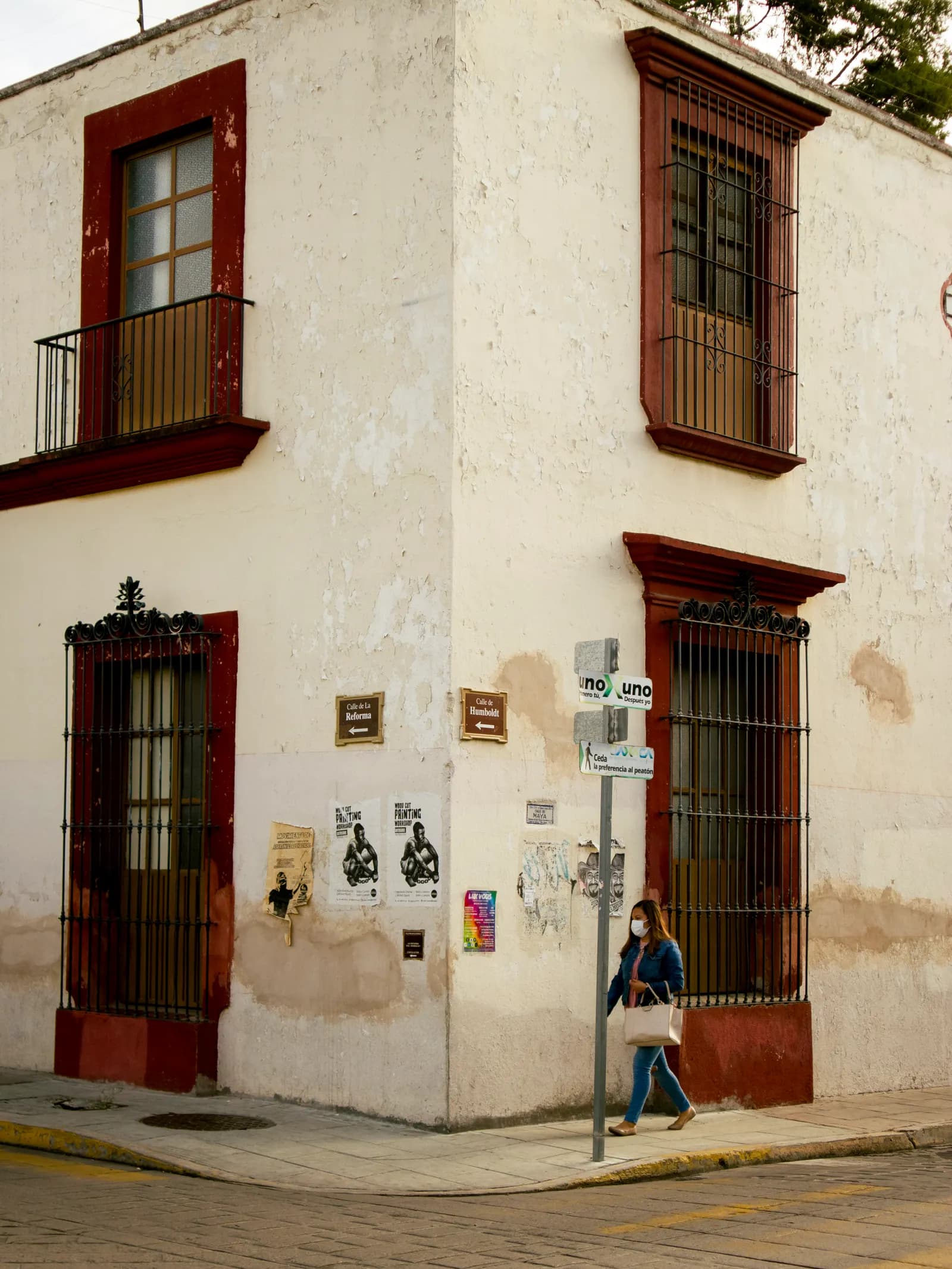 Pedestrian walking past a white building in Oaxaca